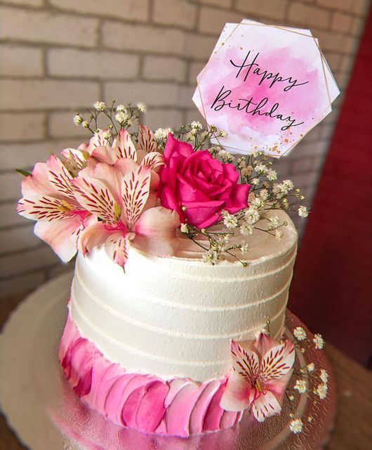 a white cake with pink flowers and a happy birthday sign on it's top