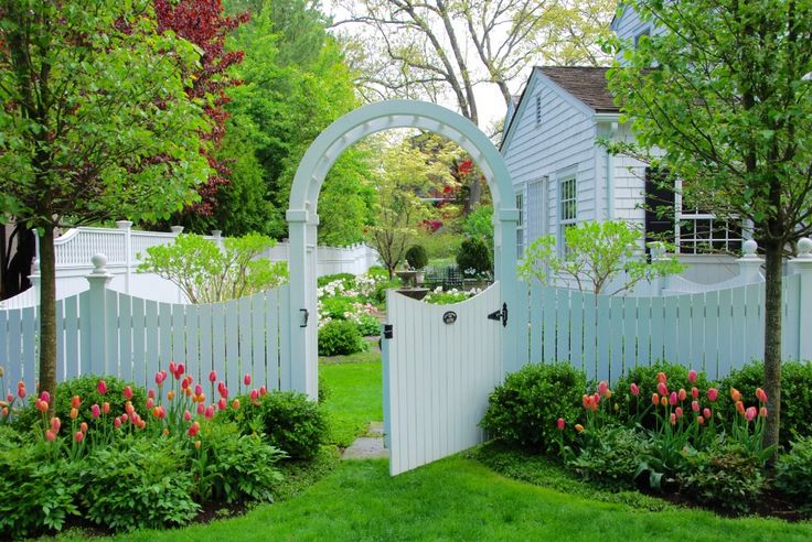 a white gate in the middle of a lush green yard