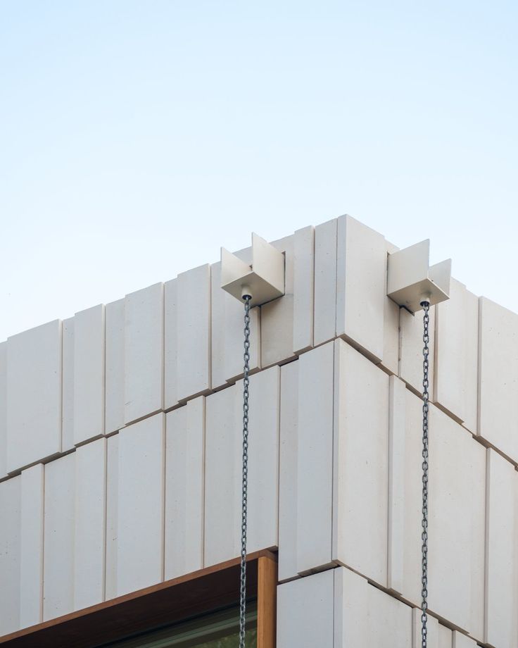 a clock on the side of a building with chains hanging from it's sides