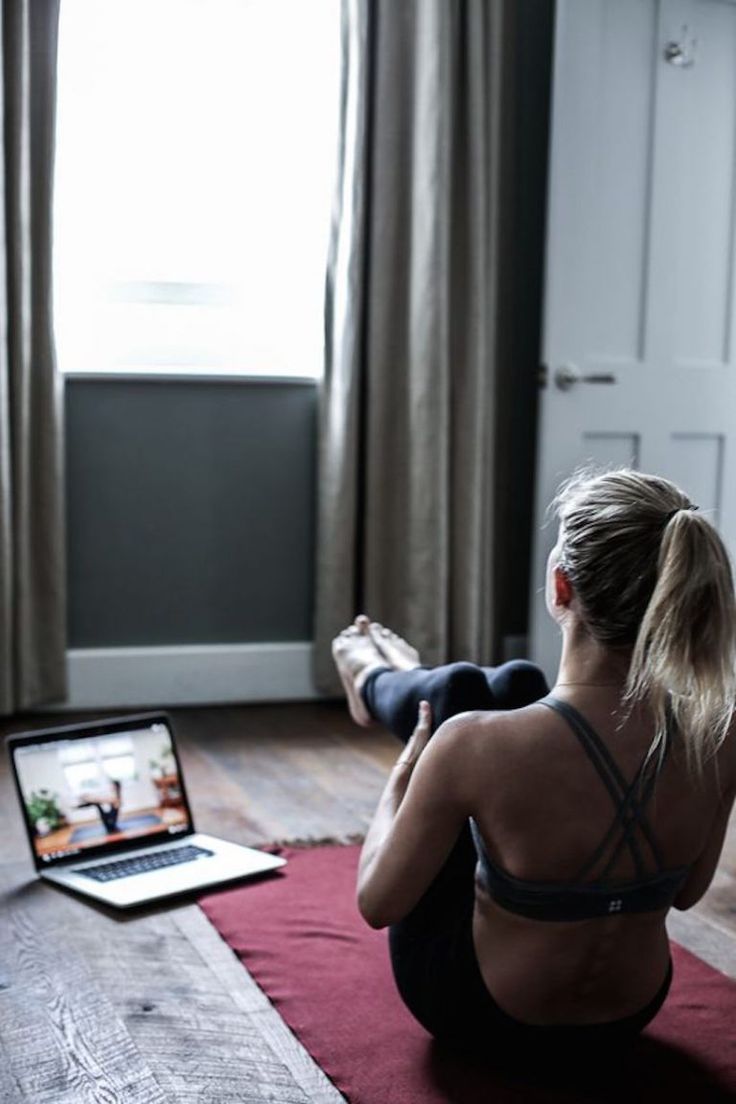 a woman sitting on the floor in front of a laptop