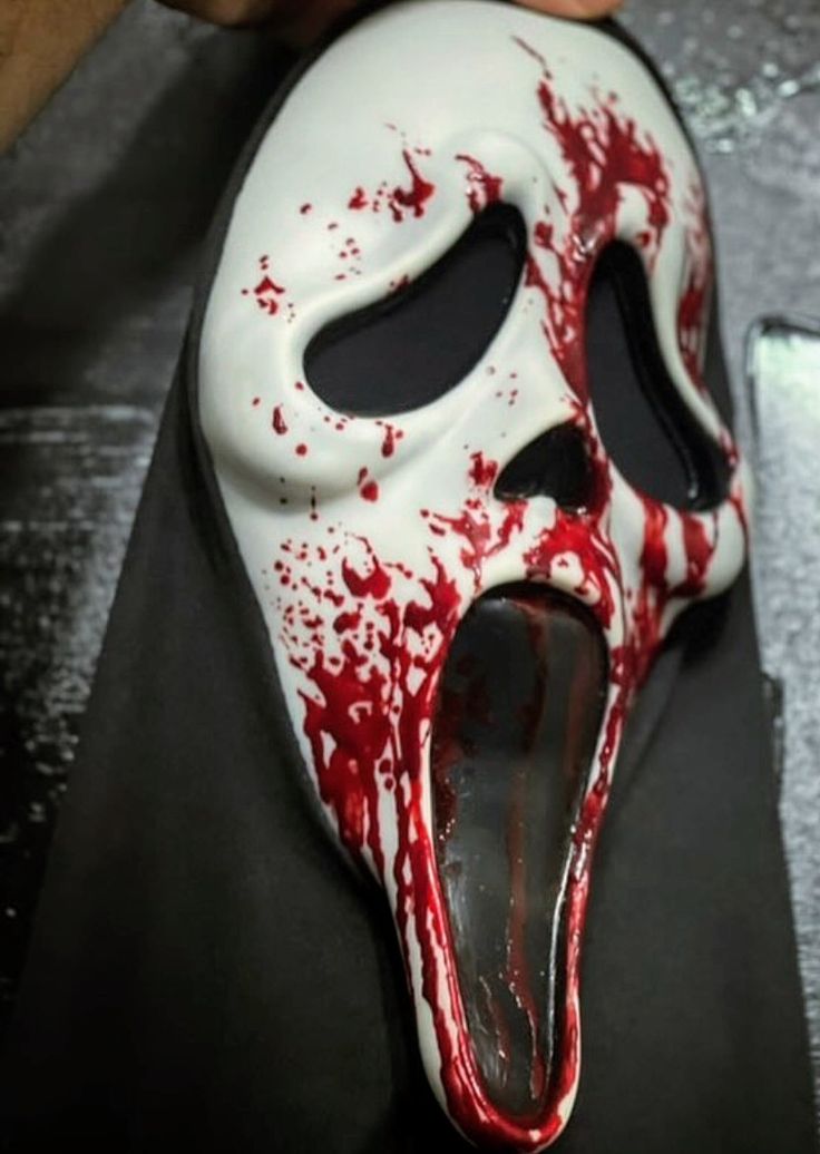 a white mask with red splattered paint on it's face and mouth