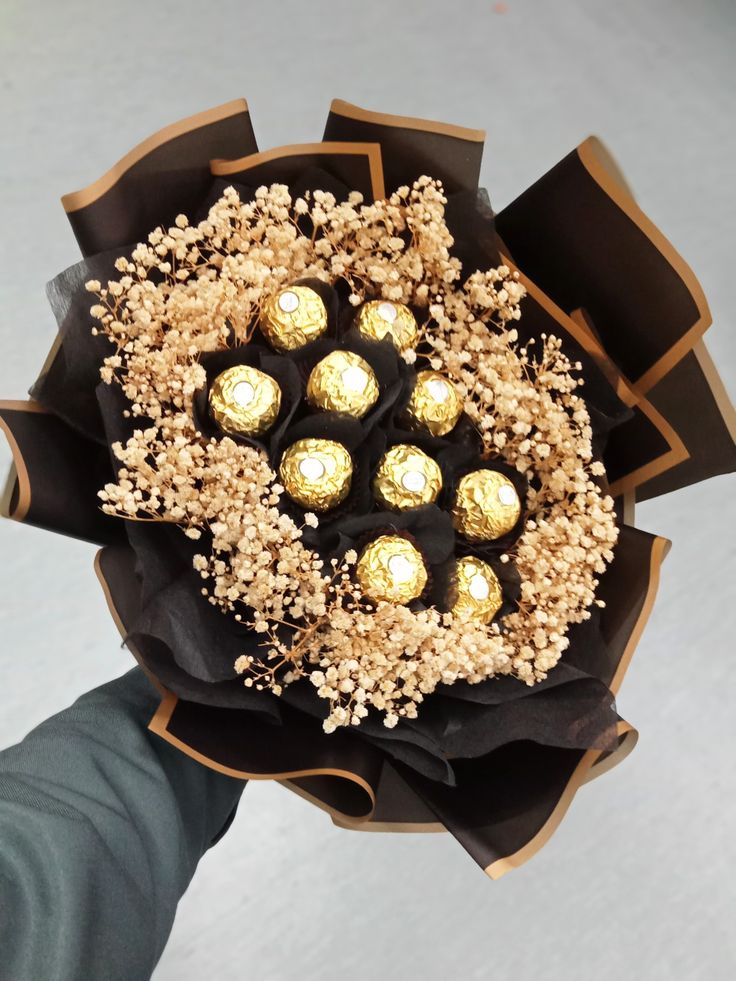 a bouquet of chocolates wrapped in black paper with gold foiled decorations on top