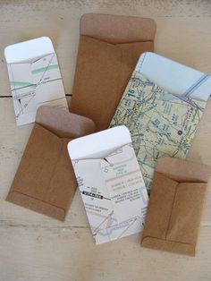 several envelopes with maps on them sitting on a table next to some paper bags