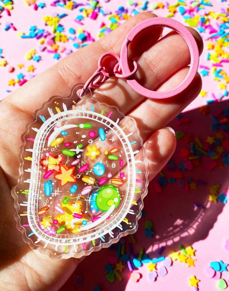 a hand holding a plastic keychain with sprinkles on it