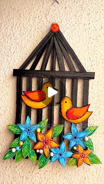 a bird in a cage with flowers and leaves on the outside, hanging from a wall