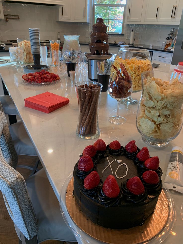 a table topped with a chocolate cake covered in strawberries next to other desserts