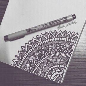 a pen sitting on top of a piece of paper next to a drawing with an intricate design