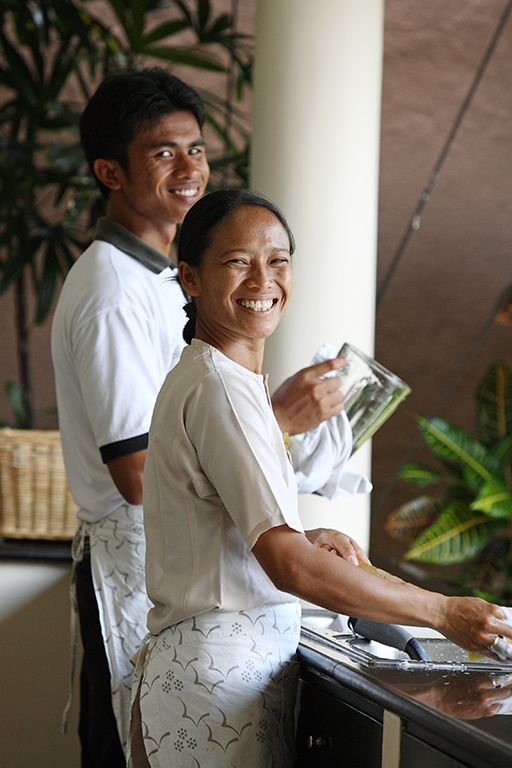 a man and woman standing at a counter in front of a window smiling for the camera