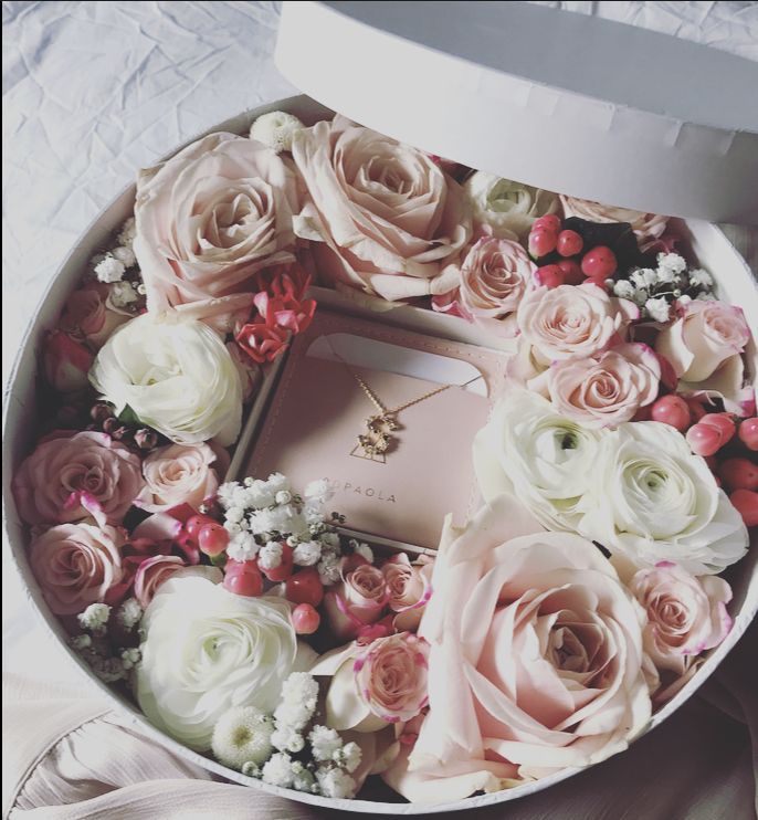 a white box filled with lots of pink and white flowers on top of a bed