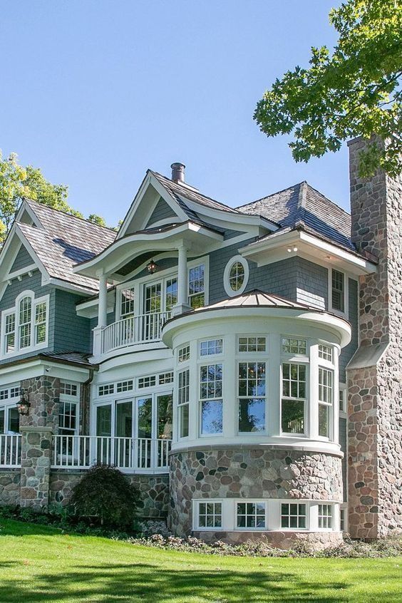 a large house that is in the middle of some grass and has windows on it