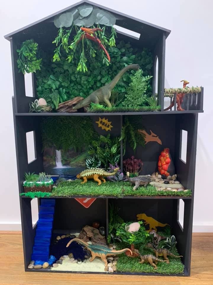 a toy house filled with dinosaurs and plants