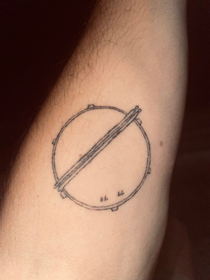 a man's arm with a circle tattoo on it and a pencil in the middle