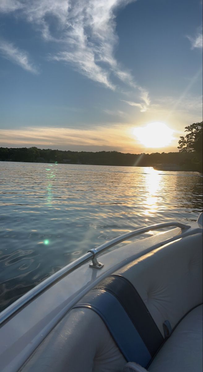 the sun is setting over the water as seen from a boat on the lake shore