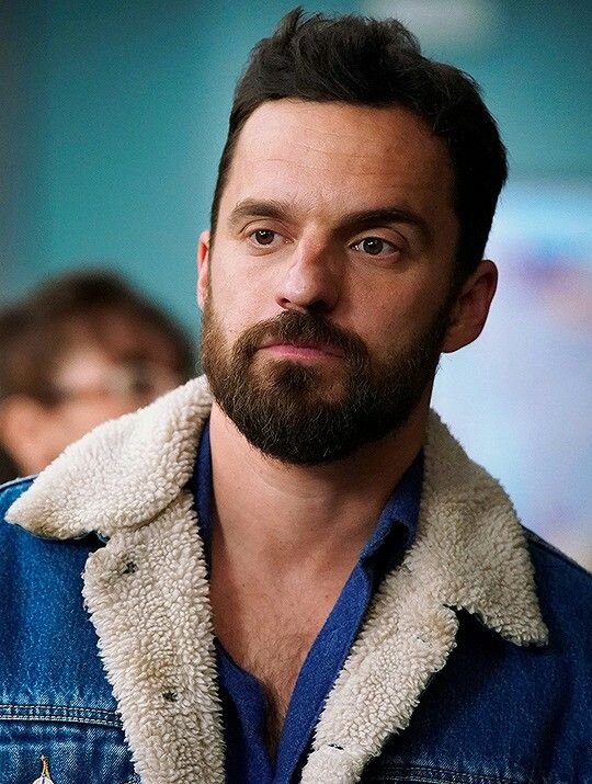 a man with a goatee and beard wearing a blue jean jacket looking at the camera