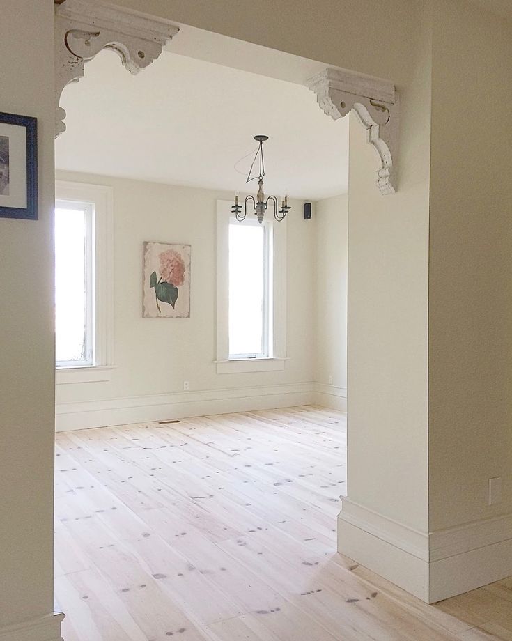 an empty room with white walls and wood floors