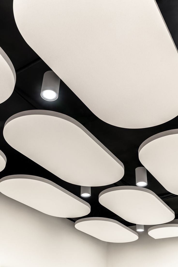 the ceiling is covered with white lights and circular shapes on black painted walls, along with recessed lighting