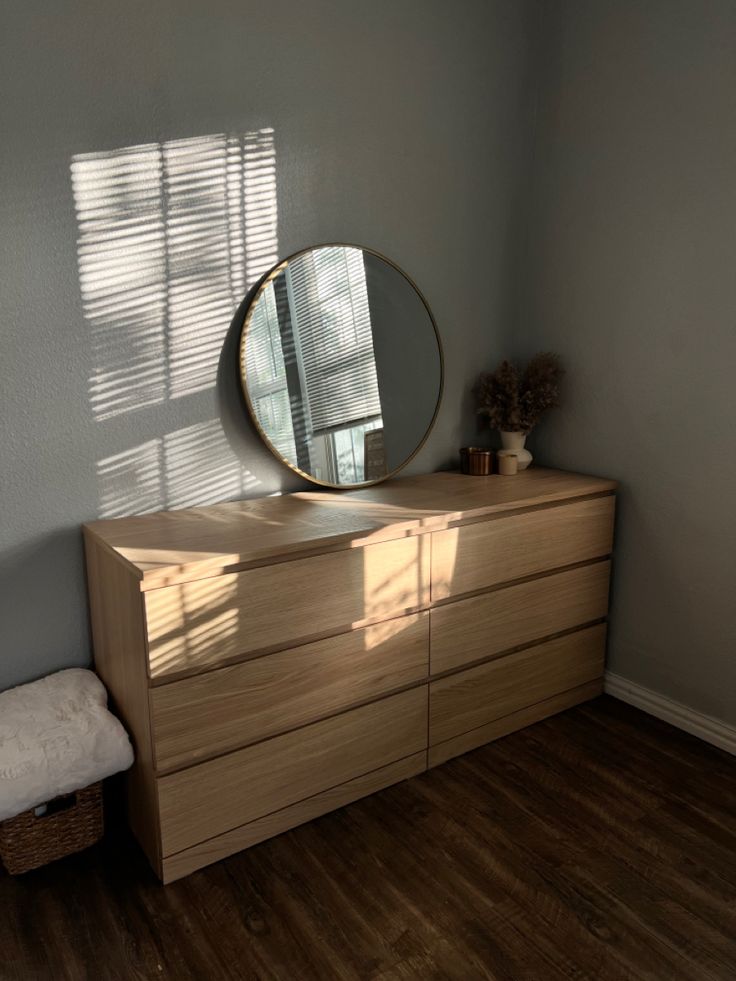 a dresser with a round mirror on top of it