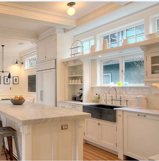 a kitchen with white cabinets and an island in front of the sink, along with two bar stools