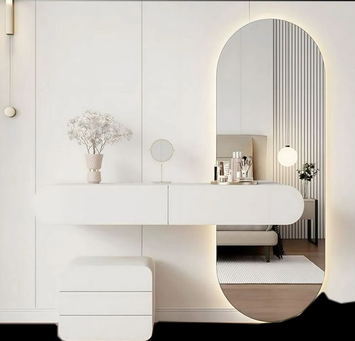 a white bathroom with an oval mirror above the sink