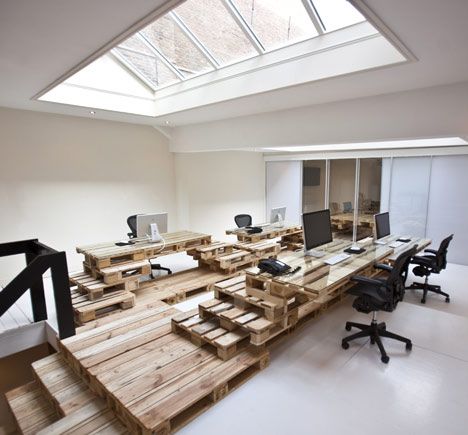 an office with wooden pallets on the floor and desks made out of wood