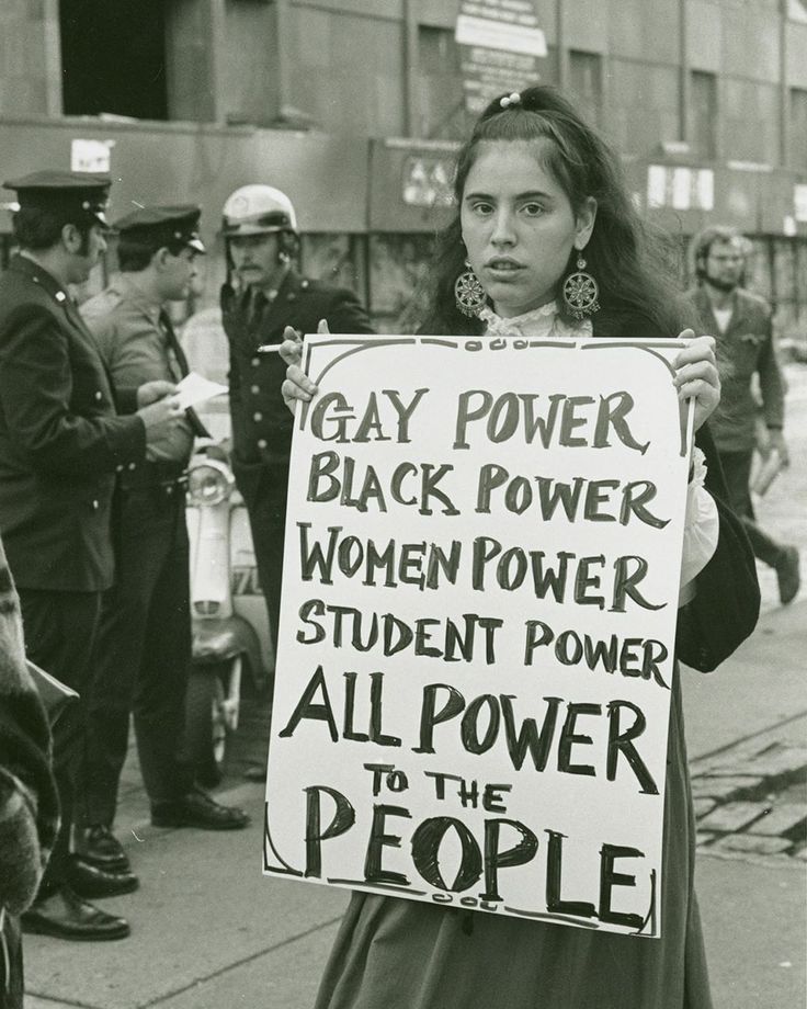 a woman holding a sign that says gay power, black power, women power, student power, all power to the people