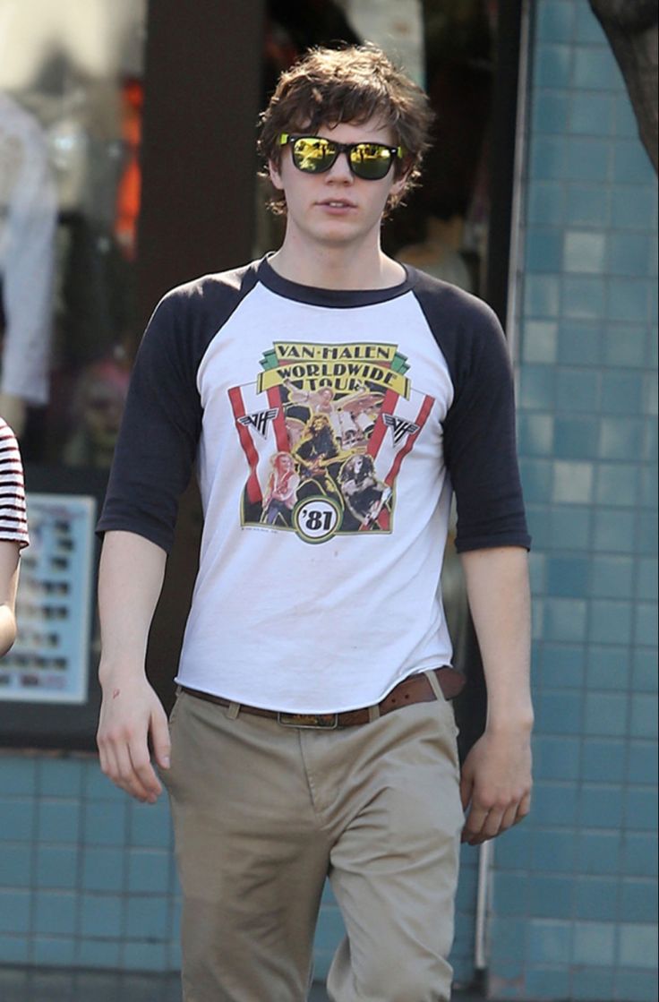 a young man walking down the street wearing sunglasses