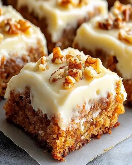 carrot cake with white frosting and nuts on top