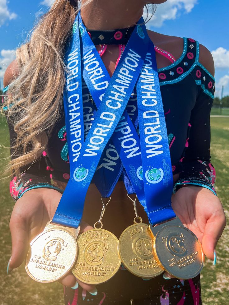 a woman holding three medals in one hand and two on the other with words written on them