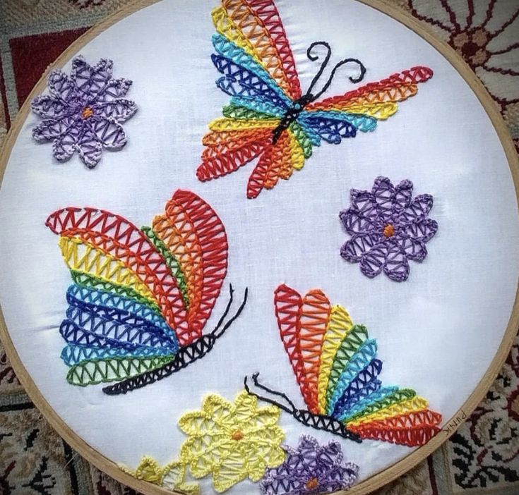 three colorful butterflies on a white embroidery hoop