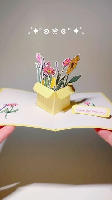 a hand holding an open book with flowers in it