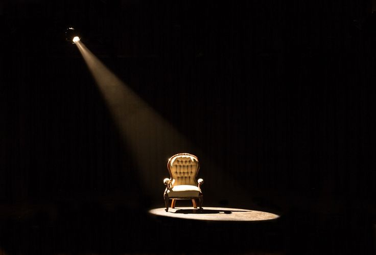 a chair sitting on top of a stage with a light coming from it's back