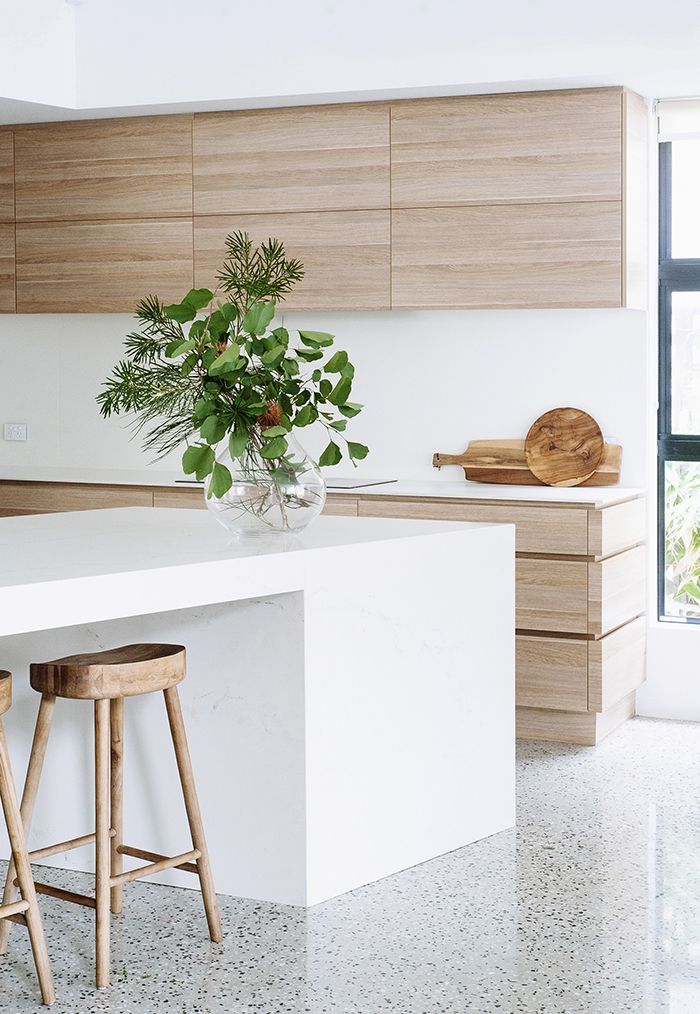 a white counter top sitting in a kitchen next to a wooden stool and potted plant