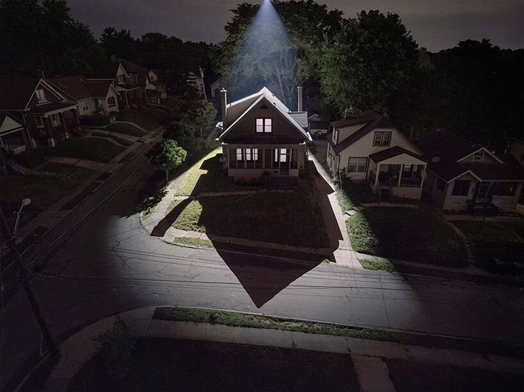 an aerial view of a house at night with the light shining on it's roof