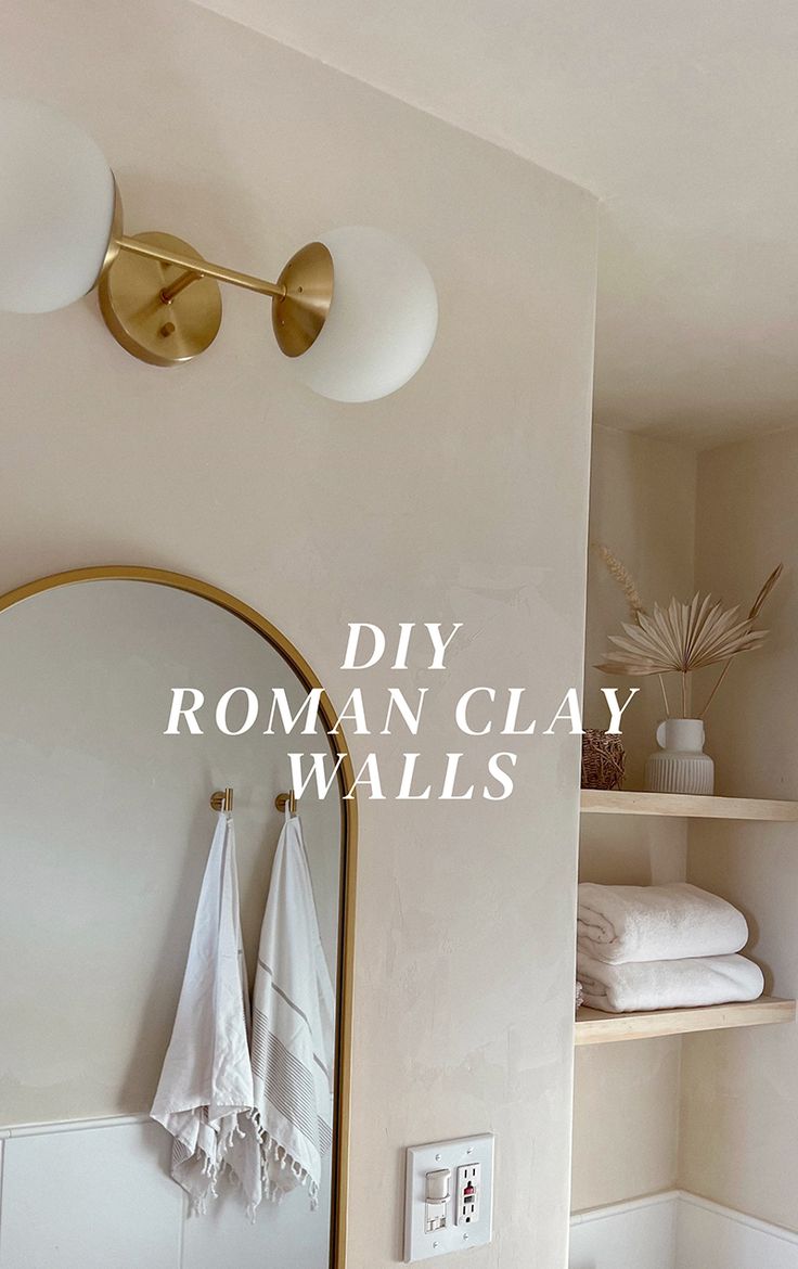 a bathroom with white towels hanging on the wall next to a gold framed mirror and light fixture