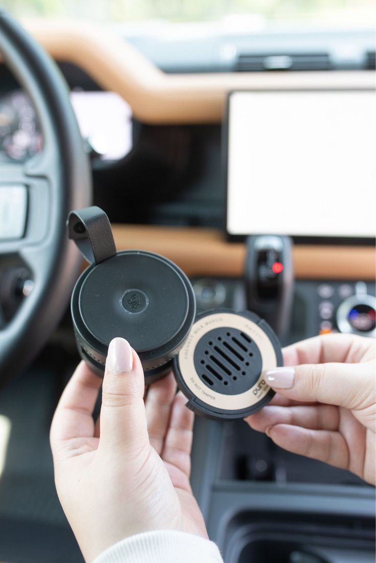 a woman is holding an air vent in her hand while driving a car with the steering wheel up