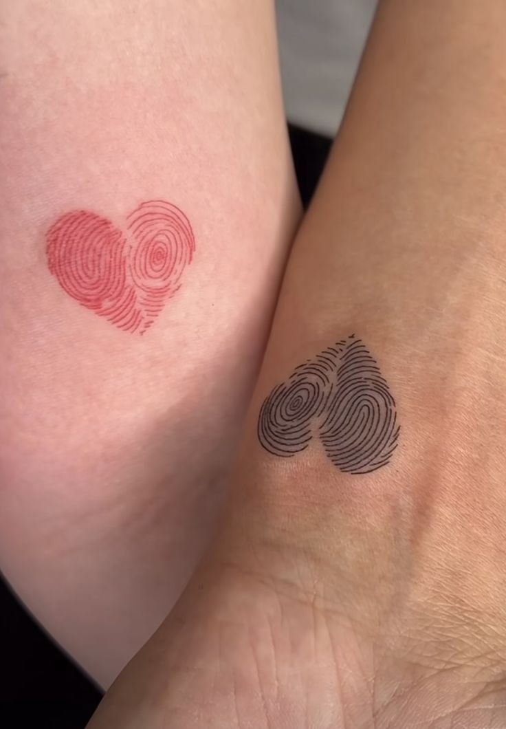 two people with matching tattoos on their legs, one has a heart and the other has a fingerprint