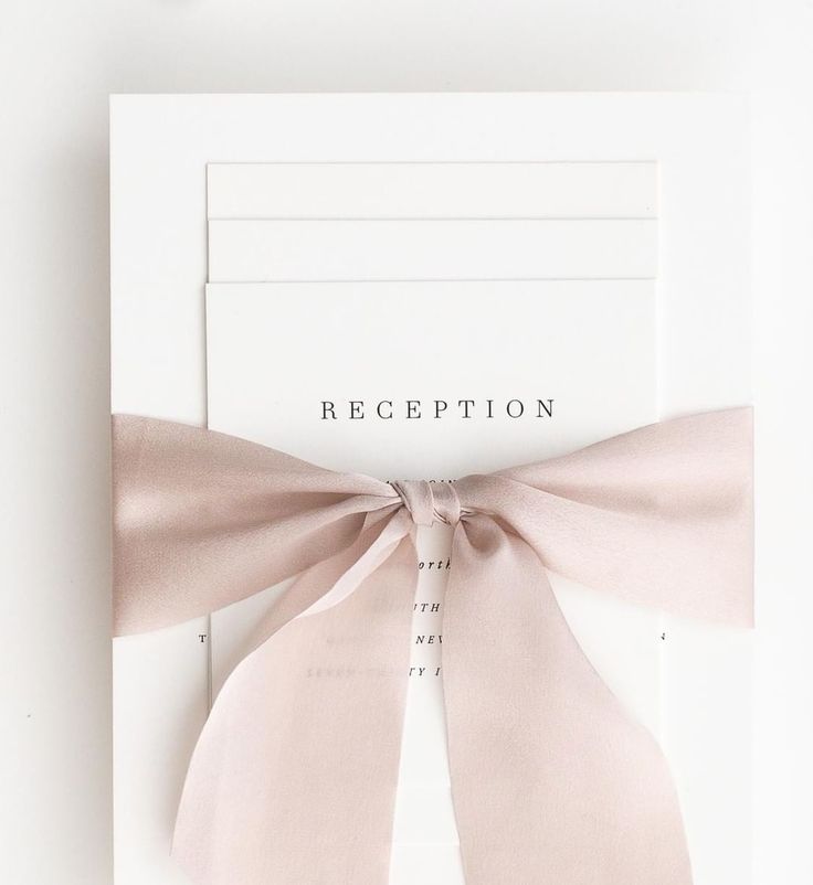 a white card with a pink bow on it and the word reception written in black