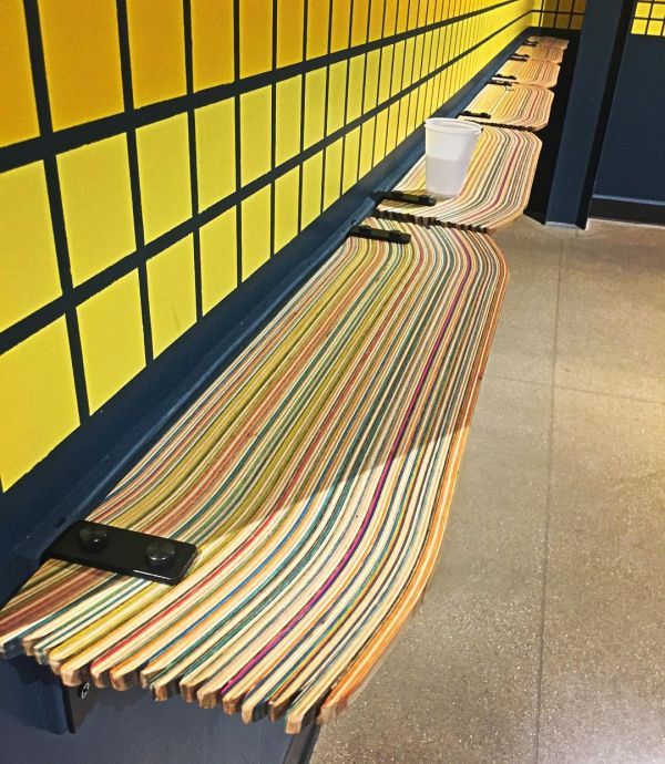 a row of benches sitting next to each other near a wall with yellow squares on it