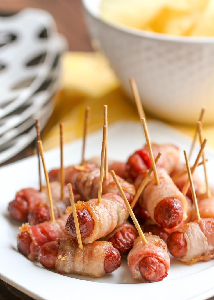 bacon wrapped hotdogs are on a plate with toothpicks in the middle