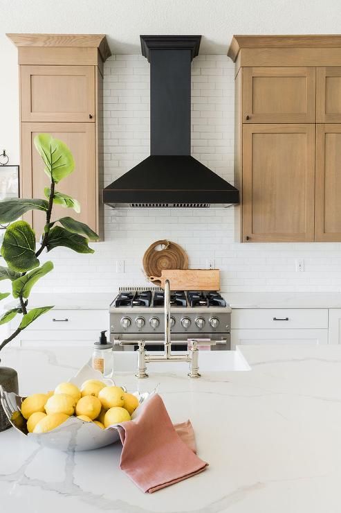 a bowl of lemons sitting on top of a kitchen counter next to a stove