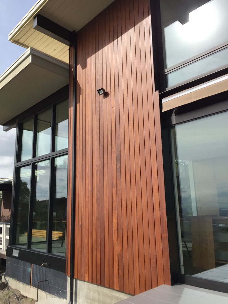 the side of a building with large windows and wood paneling on it's sides