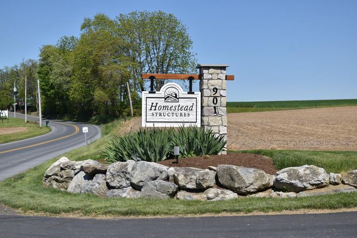 a sign for the homewood properties in front of a rural road and farm land