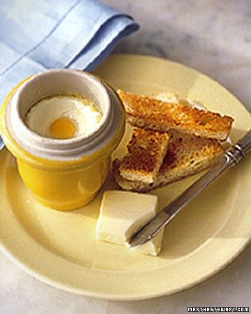 a plate topped with toast and butter next to a cup of egg yogurt