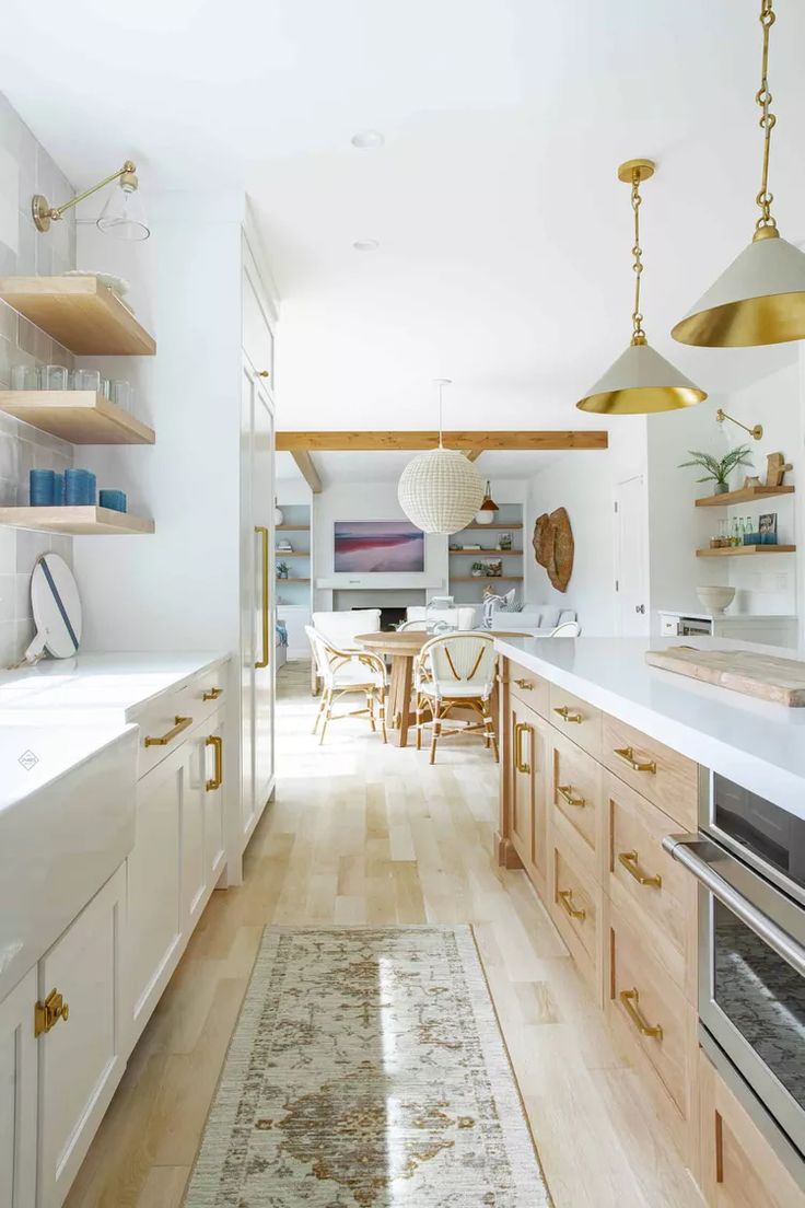 a kitchen with wooden floors and white walls, along with open shelving units on the wall