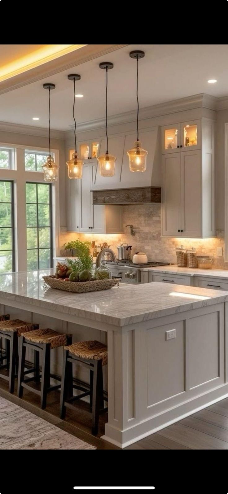 a large kitchen with an island and lots of lights hanging from the ceiling above it