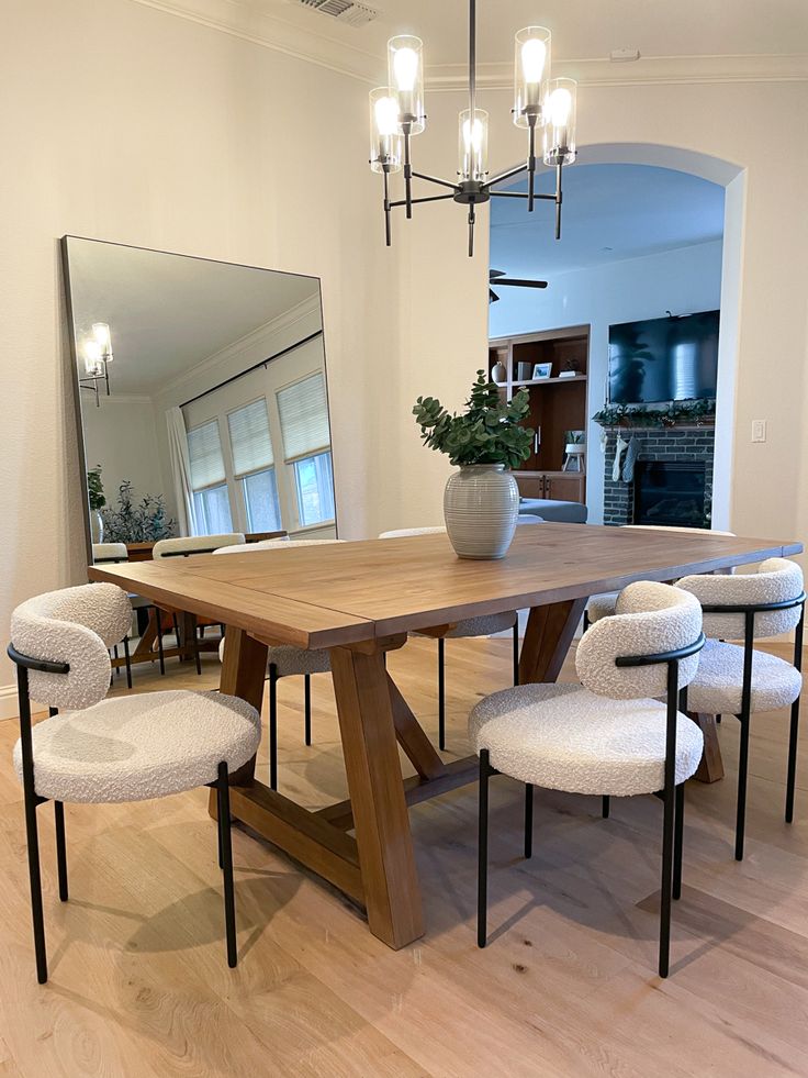 a dining room table with four chairs and a large mirror on the wall above it