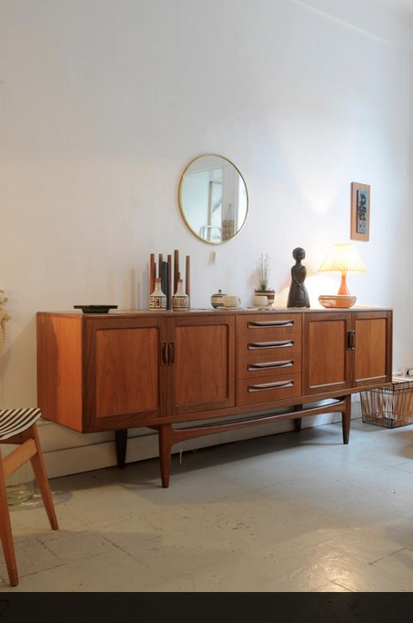 a wooden cabinet sitting in the middle of a living room next to a table and chair