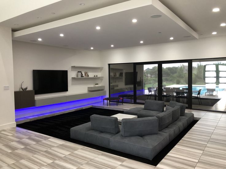 a modern living room with grey couches and blue lighting