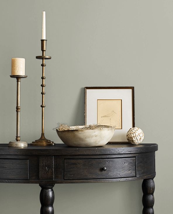 a table with a bowl and two candles on it next to a framed photograph, candle holder and other items