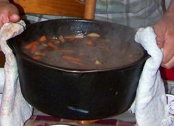 a person holding a cloth over a pot filled with food